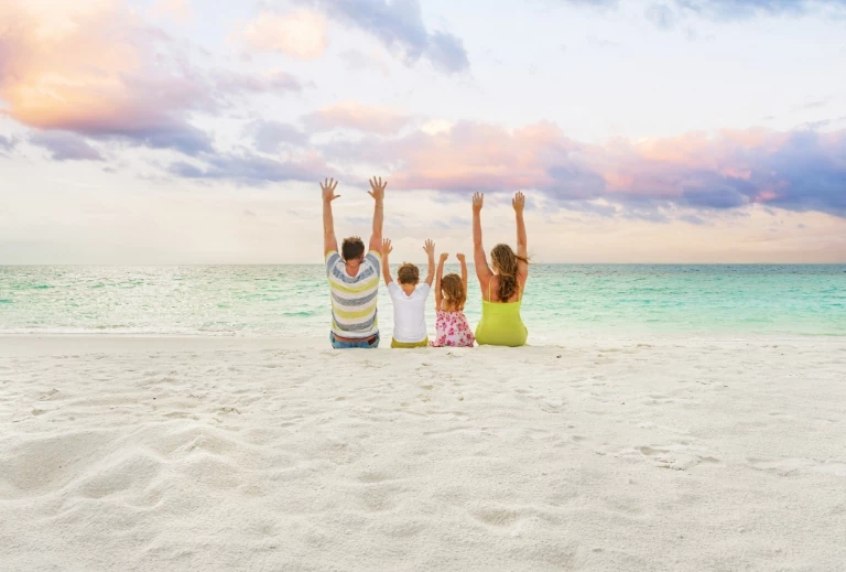rodzina z uniesionymi rękami siedząca na plaży
